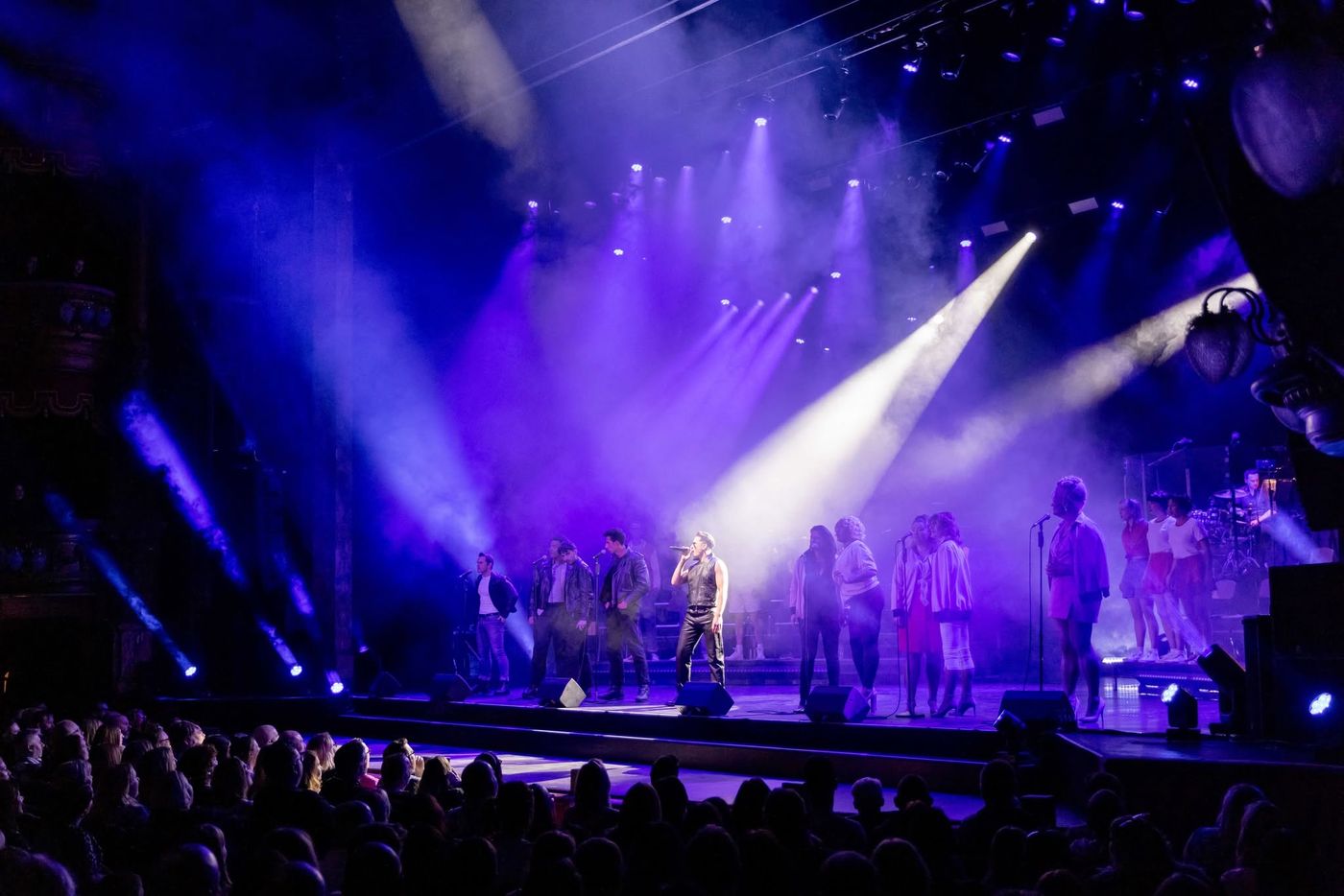 The full company on the Palladium stage under blue and purple beams