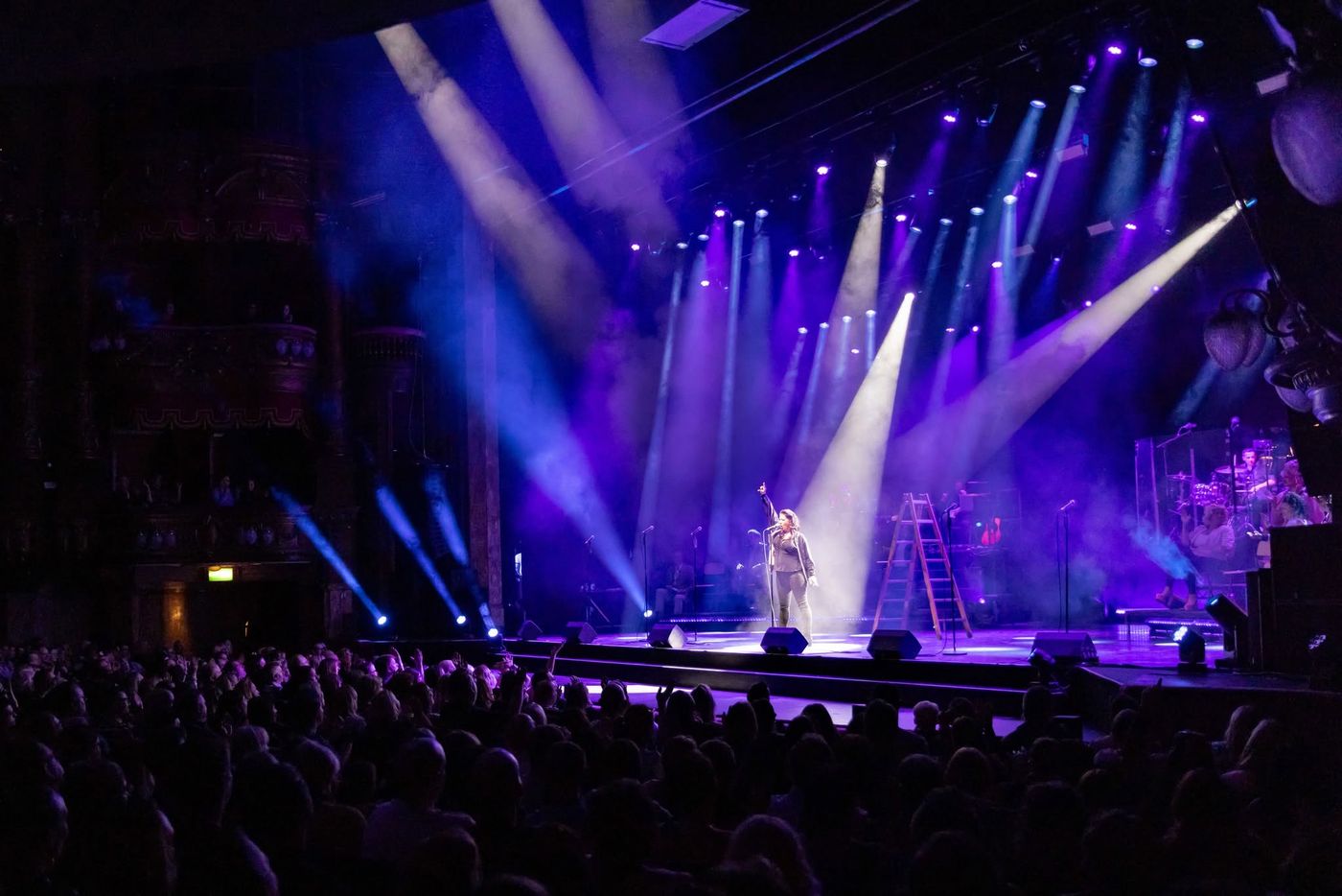 Spotlight beams crossing the stage above the band and cast