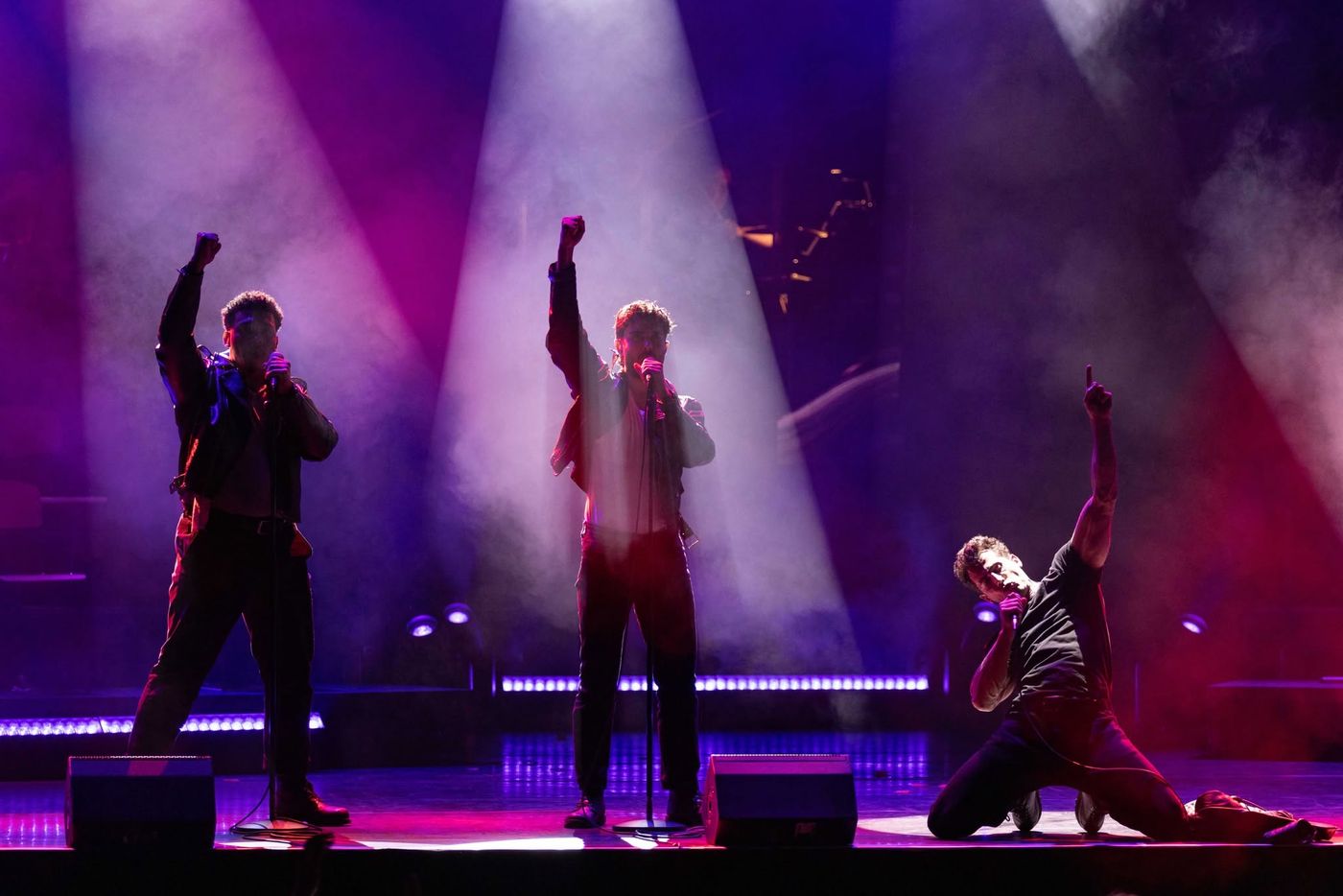 Three performers silhouetted with arms raised