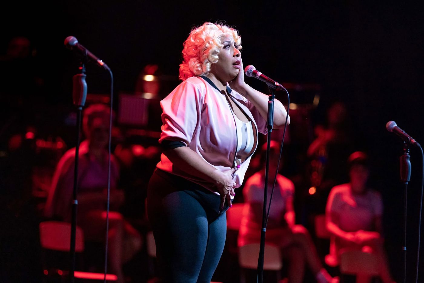 A performer singing under warm red light